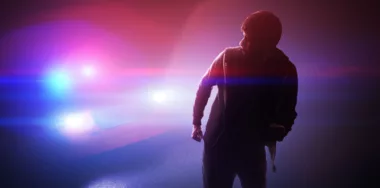 Silhouette of young man running away from a police car