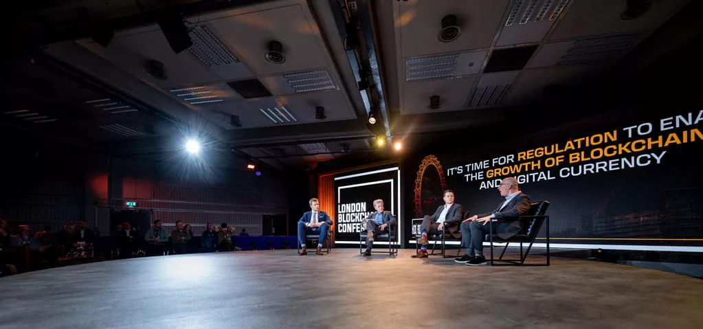Wide angle image of the panellists on stage at the London Blockchain Conference 2023