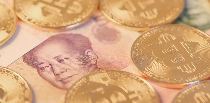 gold bitcoins on top of chinese banknotes