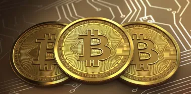 three gold bitcoins on a gold circuit background