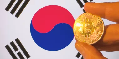 Holding a physical golden Bitcoin over the South Korea flag