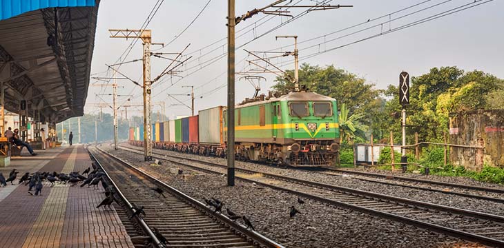 A cargo train crossing a deserted inter state railway station on a foggy winter morning in South Kolkata, India