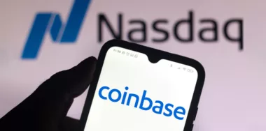 In this photo illustration the Coinbase logo seen displayed on a smartphone screen with the logo of Nasdaq in the background
