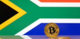 Golden bitcoin stands on a blurred background of state flag of South Africa