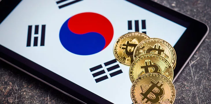 gold bitcoins on top of an ipad with korean flag on screen