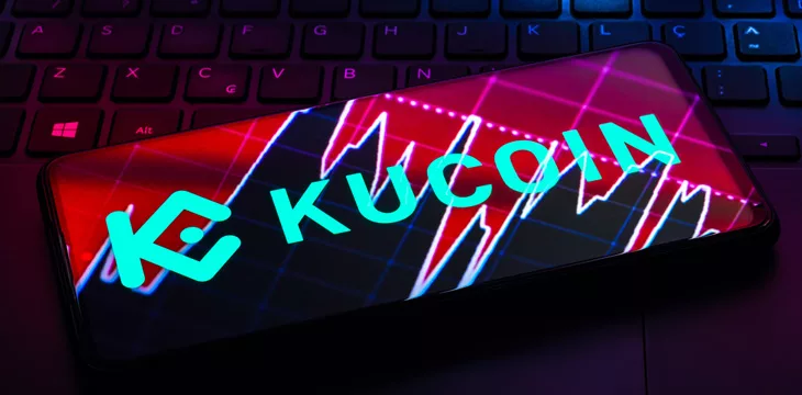 Smartphone displaying KuCoin Logo on top of a computer keyboard