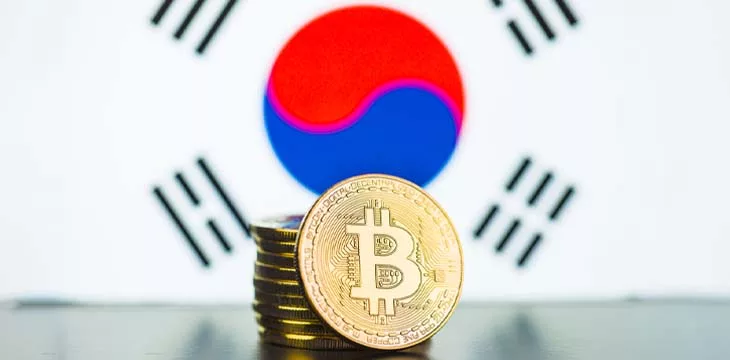 stack of gold bitcoins in front of South Korean flag