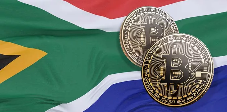two gold bitcoins in front of the flag of South Africa