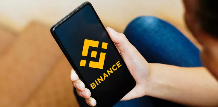 Binance logo displayed on a smartphone screen being held by a person