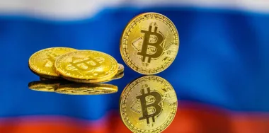 Gold bitcoins in front of the flag of Russia