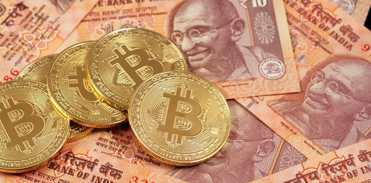 A close up image of bitcoins with Indian rupee notes