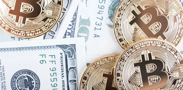 Close up image of golden Bitcoin coins on US Dollar banknotes