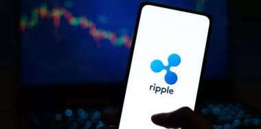 Ripple logo displayed on smartphone screen with data chart in the background