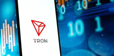 TRON logo on phone screen with stocks background