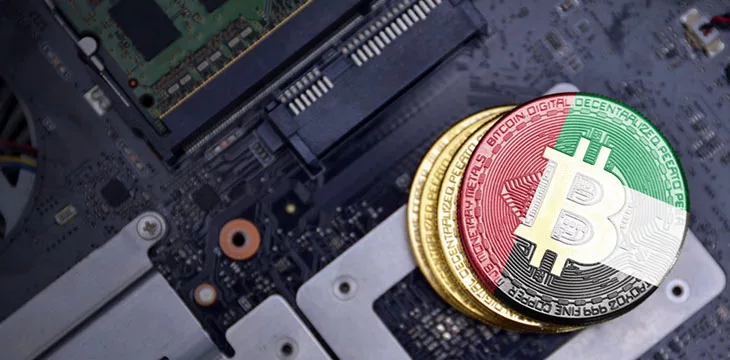 UAE flag on stack of gold bitcoin on top of a motherboard