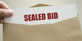 Sealed Bid text on paper being put inside brown envelope.