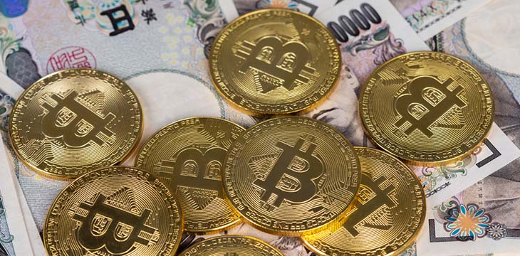 gold bitcoins on top of yen paper bills