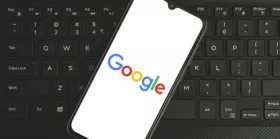 google logo on smartphone screen on top of a keyboard