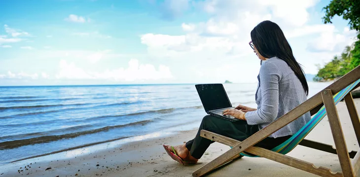 Business woman using a laptop beside the beach