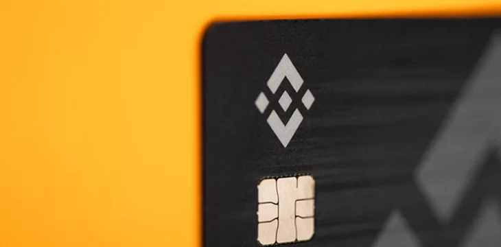 Binance cryptocurrency logo on credit card, digital payment concept with yellow background