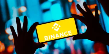 Smartphone being held by a person with logo of Binance displayed on screen