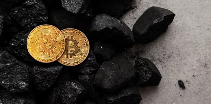 Gold bitcoin cryptocurrency coin in a pile of coal
