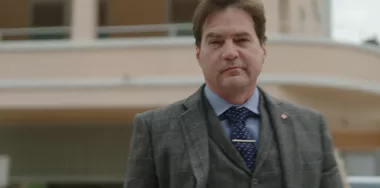 Dr. Craig Wright in a gray suit with background of a building