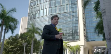 Image of Dr. Craig Wright with background of glass building and palm trees