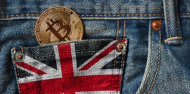 Golden Bitcoin cryptocurrency in the pocket of jeans with the flag of United Kingdom (UK) flag