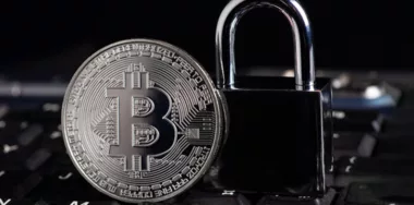 Bitcoin security concept, silver coin with padlock on computer keyboard