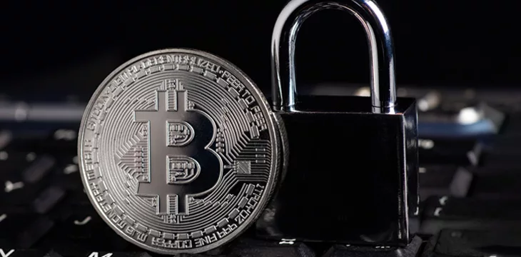 Bitcoin security concept, silver coin with padlock on computer keyboard