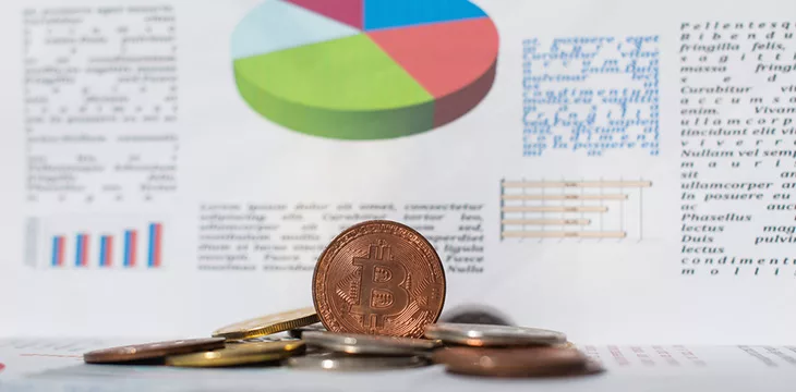 selective focus of bitcoins near paper with charts and business information on blurred background