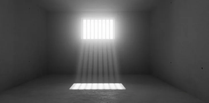 Empty, dark prison cell or gaol with sunlight rays