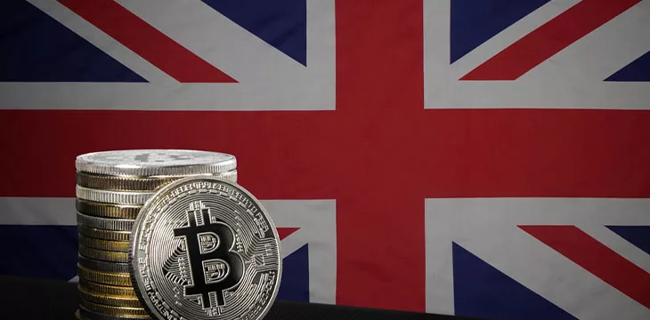 stack of silver bitcoins in front of UK flag