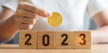 man holding a bitcoin at the back of 2023 wooden blocks