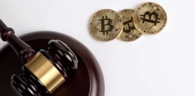 Golden bitcoin with a wooden judges gavel on white background