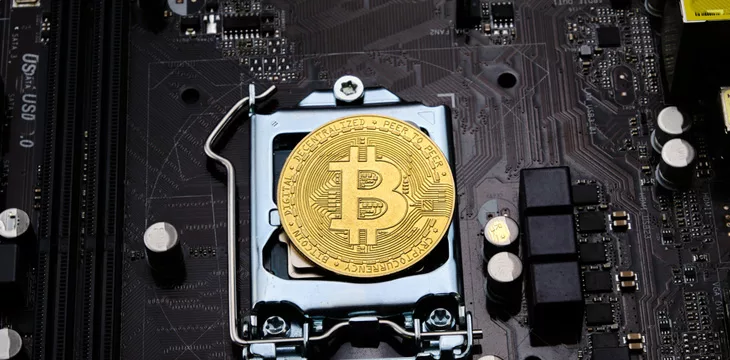 Close-up of a gold bitcoin on top of a pile of circuits
