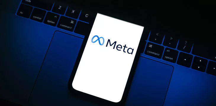 Modern computer with smartphone displaying Meta logo