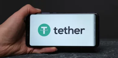 Tether logo displayed on smartphone screen being held by hand