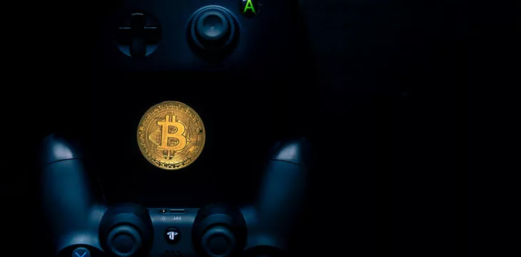 gold bitcoin in between two game consoles