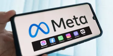 hand holding and phone with Meta logo and meta apps on screen