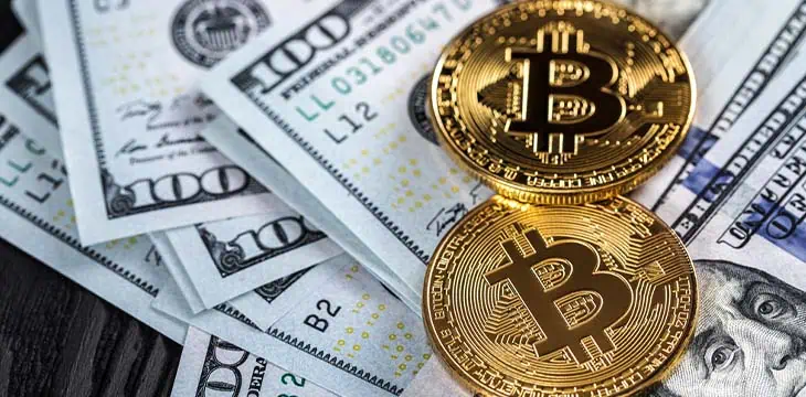 Golden bitcoin coins on U.S. dollars close up