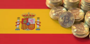 Stacks of golden Bitcoins on flag of Spain