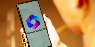 Microsoft Copilot logo on a phone held by a hand