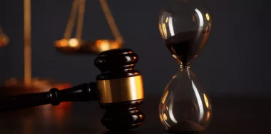 Judges gavel, scales of justice and hourglass on wooden table