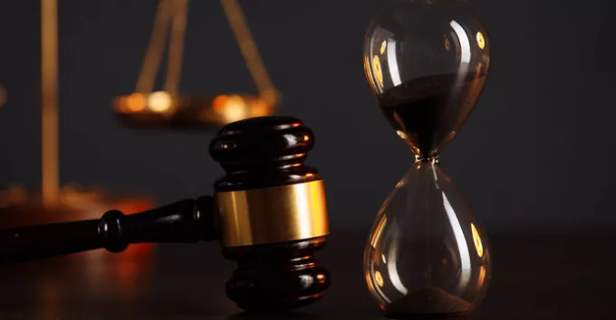 Judges gavel, scales of justice and hourglass on wooden table