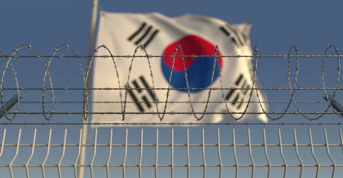 Barbed wire against waving flag of South Korea