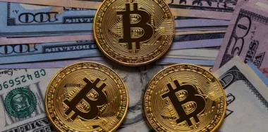 Golden Bitcoin coins and US dollars on wooden table