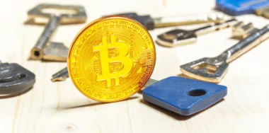 Bitcoin coins and keys on wooden table