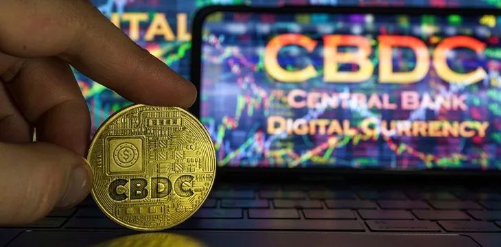Central Bank Digital Currency logo on a coin and laptop